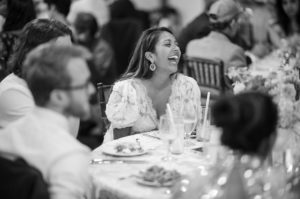 A woman laughs while sitting at a table at a summer wedding at Riverside Farm.