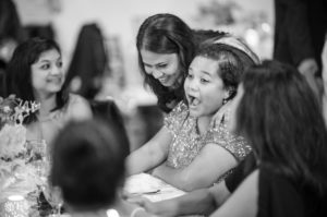A woman joyfully laughs at a table at a summer wedding reception.