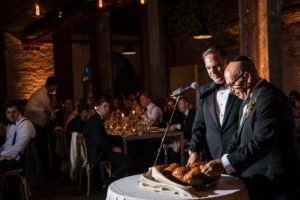 Two men cutting a loaf of bread at a New York wedding reception.