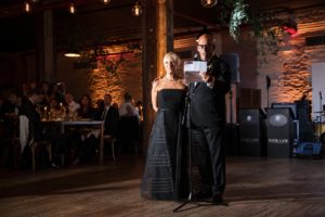 A man and woman standing in front of a microphone at a wedding reception in New York.