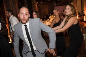 A man in a suit dancing at a wedding reception in New York.