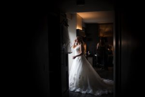 A bride in a wedding dress standing in a dimly lit room.
