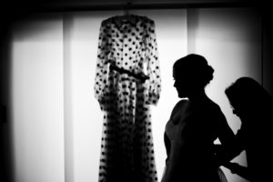 A silhouette of a woman in New York looking at a dress hanging on a hanger for her wedding.