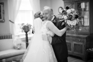 A black and white photo of a bride hugging her father on her wedding day in New York.