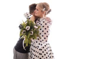 A man and woman embracing affectionately in front of a white background.