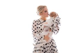 A woman in a polka dot dress holding a dog at a wedding in New York.