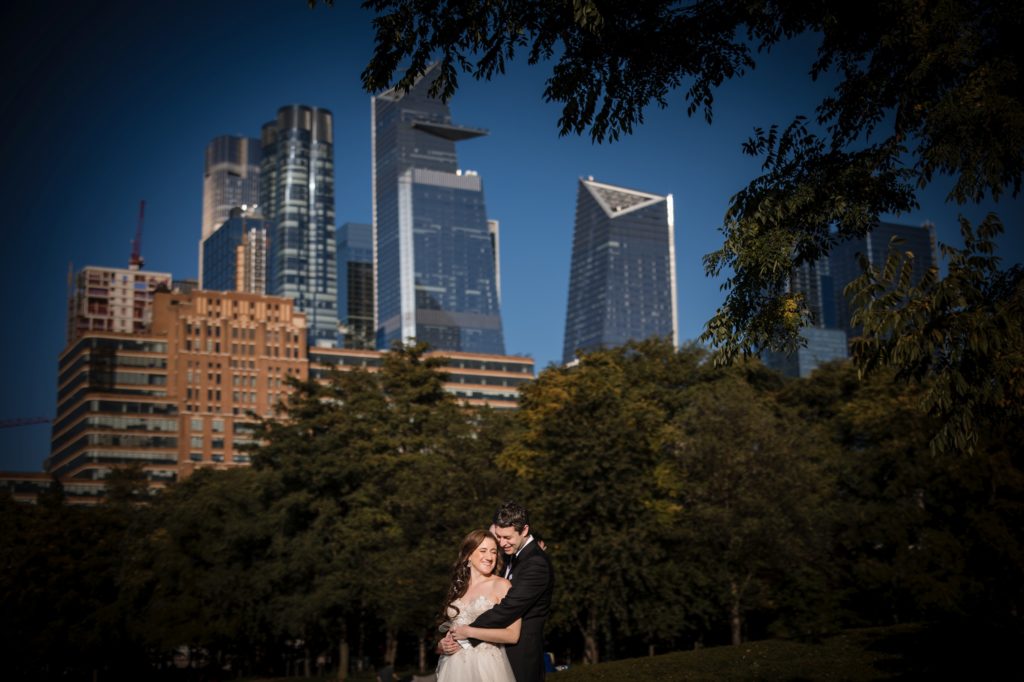 A wedding couple embracing in front of the New York city skyline.