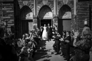 A black and white photo of a wedding party exiting a church in New York.