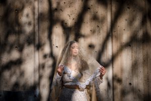 A New York bride wearing a veil in front of a concrete wall.
