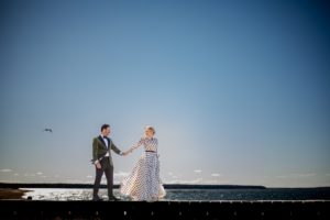 A bride and groom standing on a dock near the water in New York during their wedding.