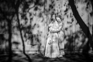 Two women in New York pose in front of a tree, captured in a black and white photo.