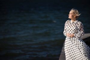 A woman in a polka dot dress standing on a dock in New York.