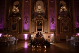 A wedding reception in an ornate ballroom with purple lights in New York.