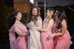 Bridesmaids in pink saris posing for a wedding photo.