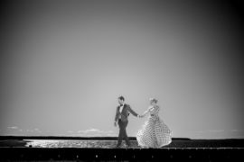 A black and white photo of a couple walking on a dock in New York.
