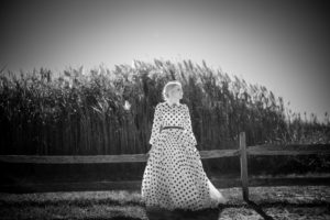 A woman in a polka dot dress standing next to a fence during a wedding ceremony in New York.