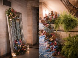 A beautifully adorned mirror covered in flowers and greenery stands gracefully in front of a stunning New York staircase, creating an enchanting ambiance perfect for a dreamy wedding.