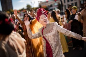 A man in an indian turban dancing in a wedding crowd in New York.