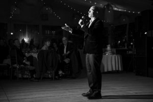 A man is speaking into a microphone at a wedding in New York.