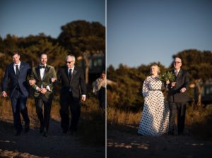 A newly married couple walking down the beach with their wedding party.