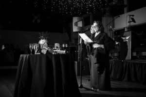 A vintage black and white photo captures a woman giving an impassioned speech at a party in New York.
