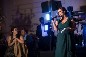 A woman in a green dress speaking into a microphone at a wedding in New York.