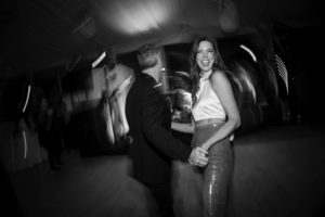 A black and white photo capturing a couple dancing joyfully at a wedding in New York.