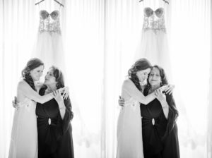 A bride and her mother hugging in front of a New York wedding dress.