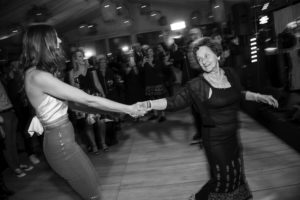 At a wedding party in New York, a woman warmly shakes hands with an older woman.