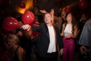 A man and woman holding red balloons at a wedding party in New York.