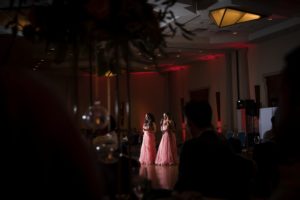 Two bridesmaids in pink dresses standing in a dark room during a wedding in New York.