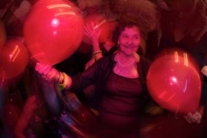 A woman holding red balloons at a wedding party.