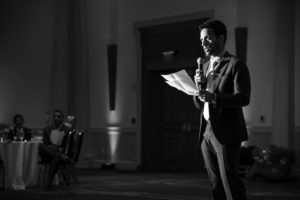 Black and white photo of a man giving a speech at a wedding in New York.