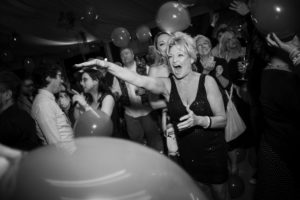 Black and white photo of a woman holding balloons at a wedding party in New York.