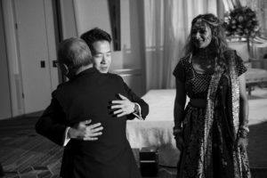 A man is hugging a woman at their New York wedding in a black and white photo.