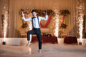 A man jumping in the air with sparklers at a wedding in New York.