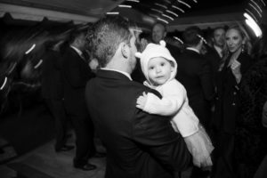 A man holding a baby at a wedding party in New York.