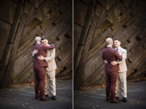Two men hugging in front of a stone wall at a New York wedding.