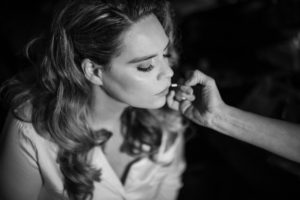 A black and white photo of a woman getting her makeup done for her wedding in New York.