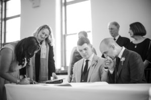 A bride and groom signing their wedding vows at a table in New York.