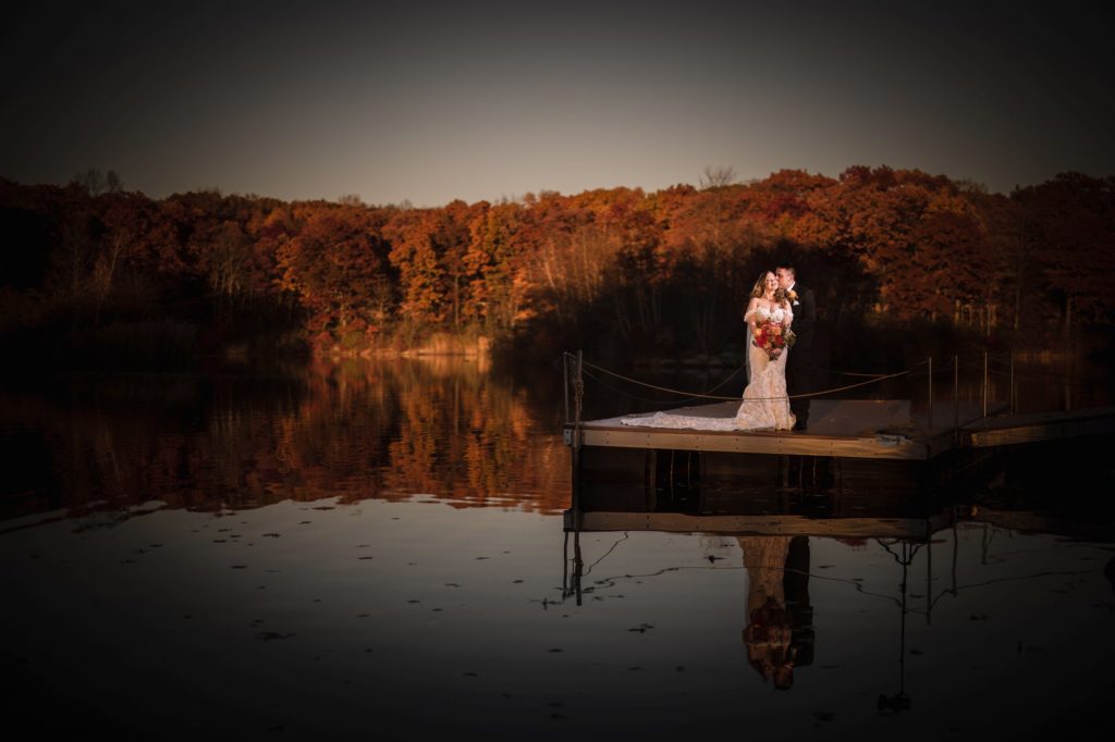 A bride and groom standing on a dock at sunset in New York, celebrating their wedding.