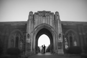 A black and white photo of a couple standing in front of an archway during their wedding ceremony in New York.