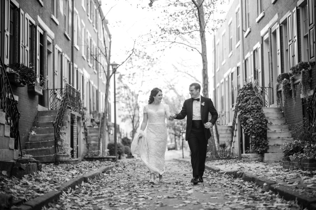 A bride and groom walking down a New York street in a black and white wedding photo.