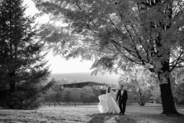 A black and white photo of a bride and groom walking in a park in New York on their wedding day.