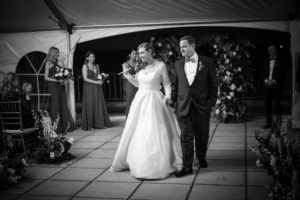 A bride and groom walking down the aisle in a New York wedding tent.