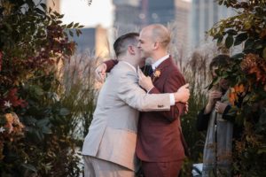 Two grooms hugging in front of the New York city skyline on their wedding day.