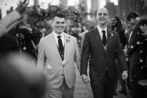 Two men in suits walking down the wedding aisle.
