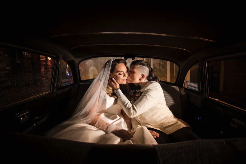 A newly married couple shares a tender kiss in the back seat of a car after their wedding ceremony in New York.