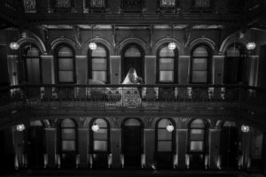A black and white photo of a bride standing in an ornate building during her New York wedding.