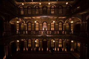 A bride and groom standing in an ornate building at their enchanting New York wedding, illuminated by the glow of the night.